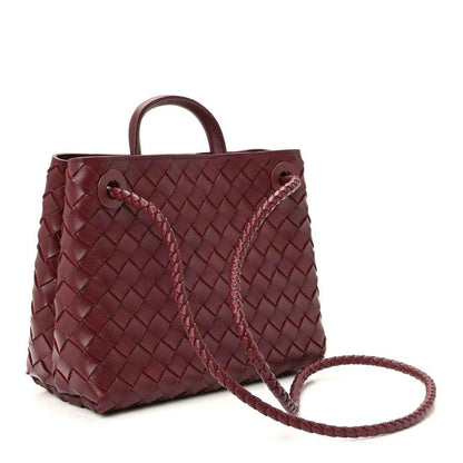 Small burgundy leather tote bag with intrecciato weave, top handle and crossbody strap.