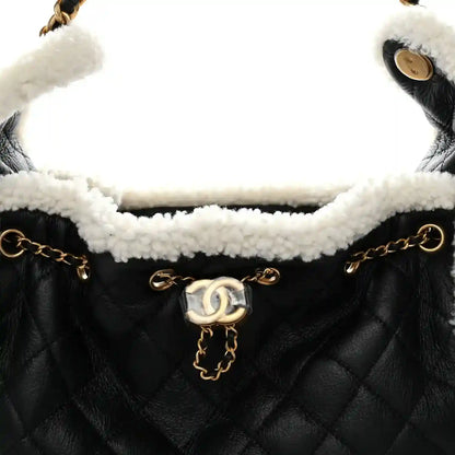 Black quilted handbag with white shearling interior and gold-tone chain strap