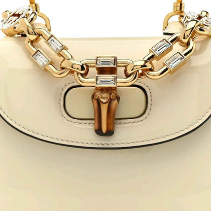 Front of white mini handbag with bamboo clasp, gold chain links, and hinged hardware