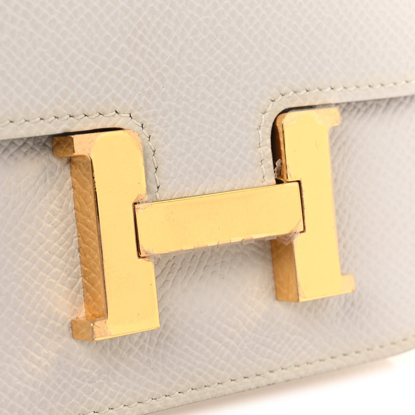 Gold-tone H clasp on pale gray textured leather flap