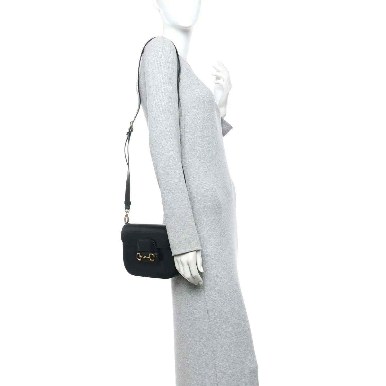 Black mini shoulder bag with gold horsebit clasp on a crossbody strap, worn on model