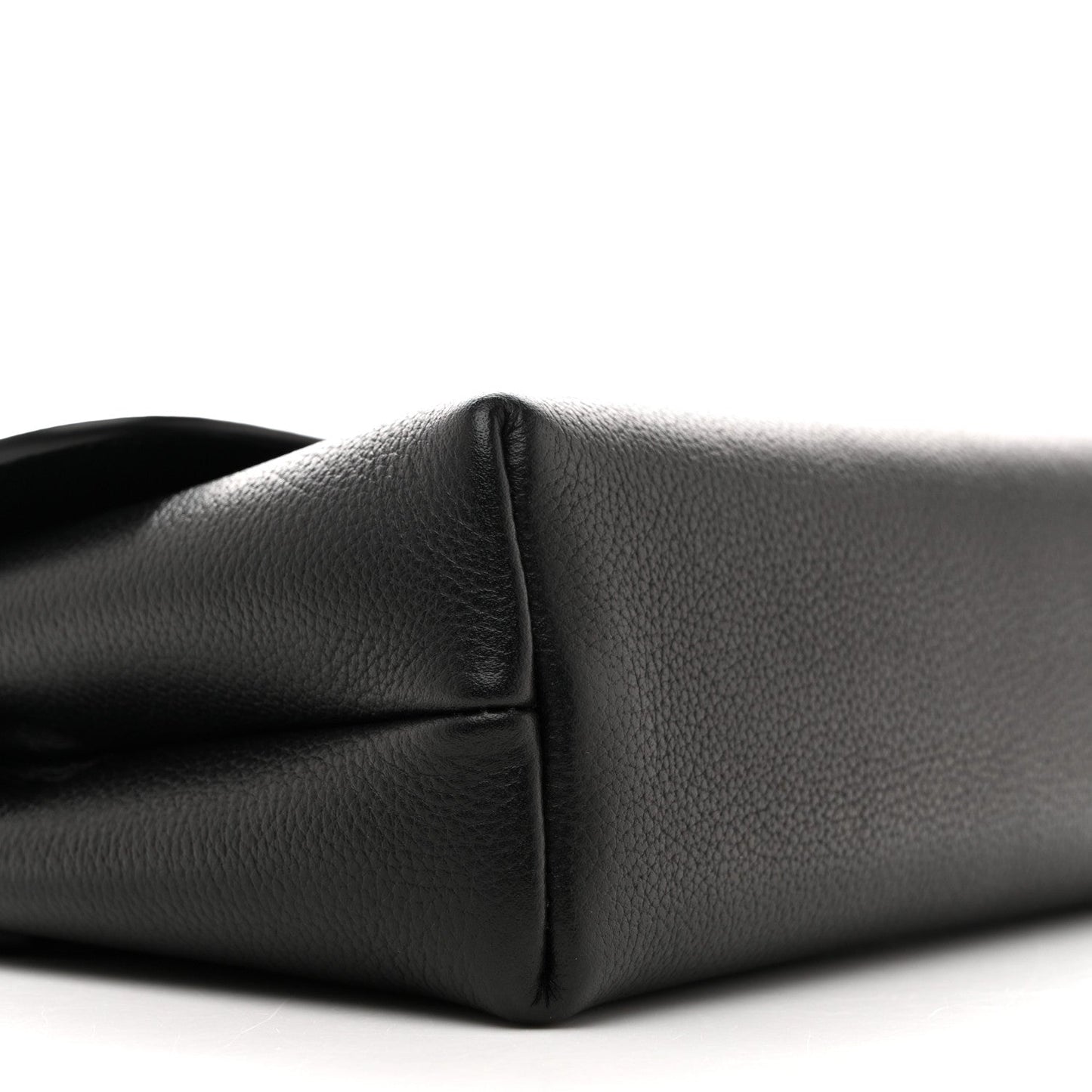 Black leather shoulder bag corner close-up showing seam and curved base