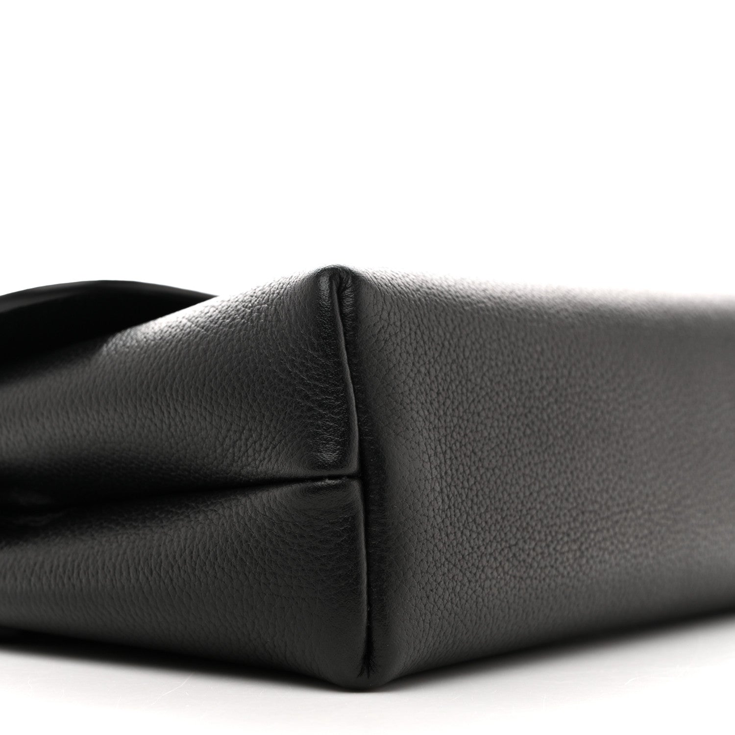 Black leather shoulder bag corner close-up showing seam and curved base