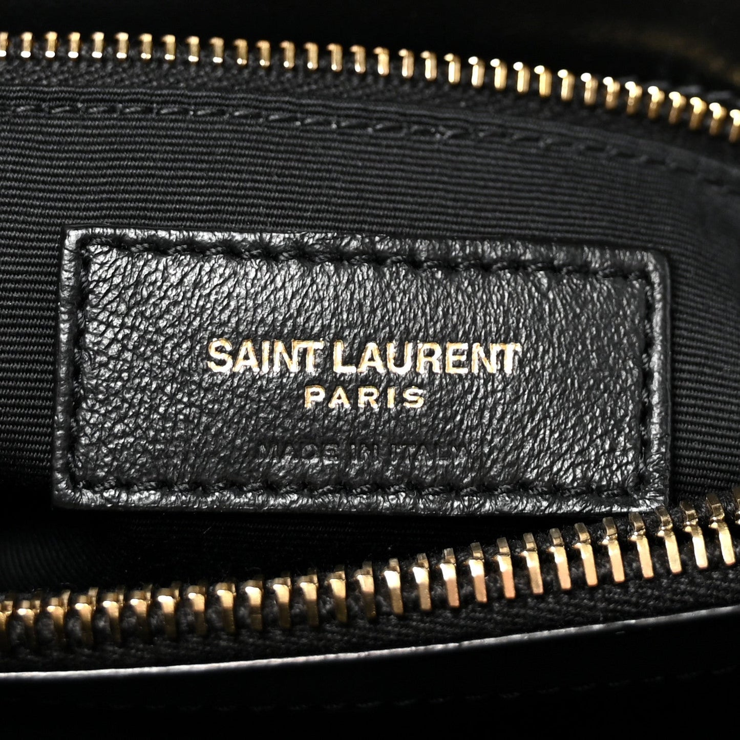 Black leather logo patch with SAINT LAURENT PARIS text and gold zipper