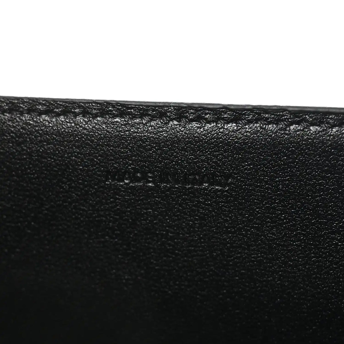 Black leather surface with subtle embossed mark on the bag