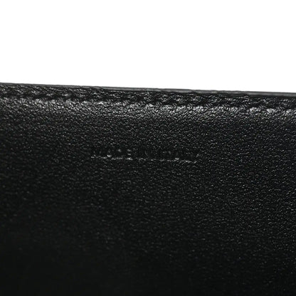 Black leather surface with subtle embossed mark on the bag