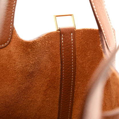 Gold-tone lock clasp and stitched seam detail on tan leather bucket bag