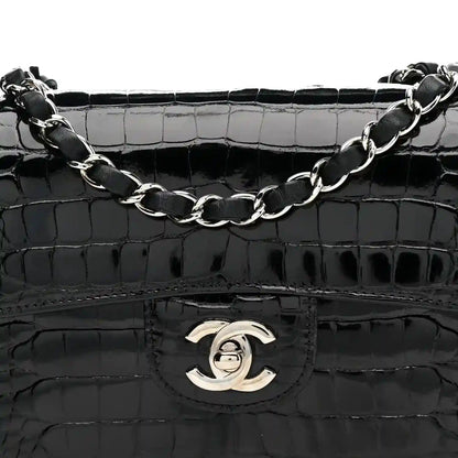Black shiny alligator flap bag with Chanel turn-lock emblem and linked chain strap.