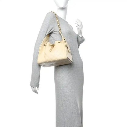 Light beige quilted handbag with chain strap, worn by model