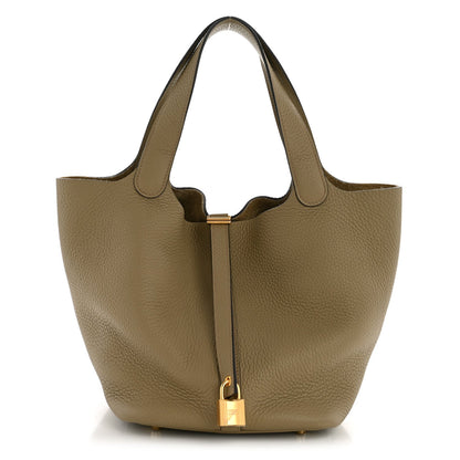 Beige leather tote with top handle, central lock closure, and gold hardware