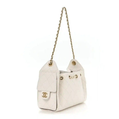 White mini handbag with quilted body, gold chain strap and front flap pocket.