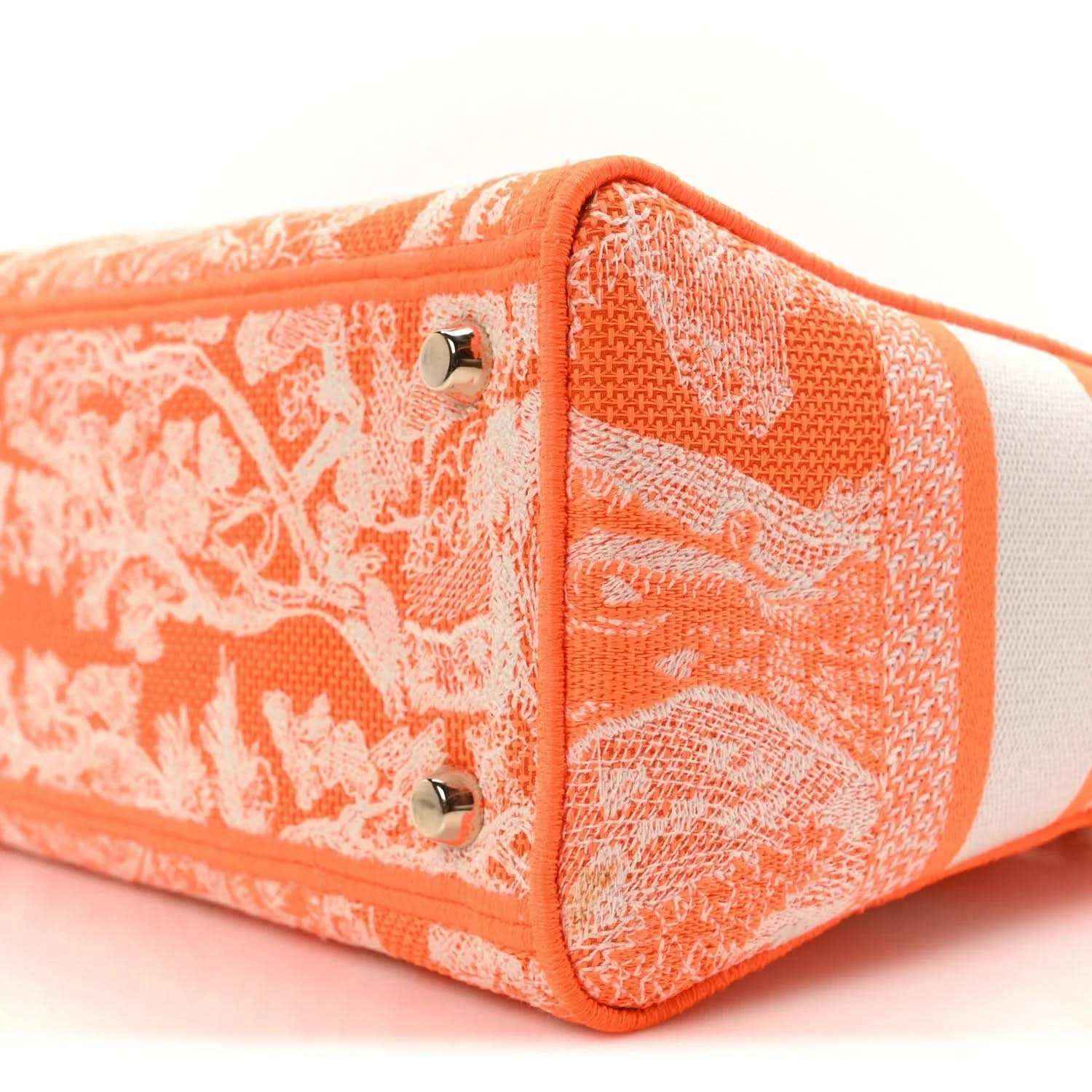 Orange embroidered bag side panel close-up with metal studs and white stripe trim.