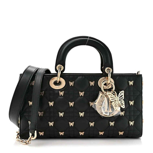 Black quilted top handle bag with butterfly motifs, gold rings, and detachable shoulder strap