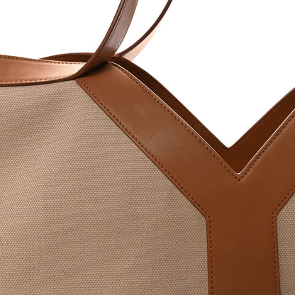 Close-up of tan canvas tote corner with brown leather strap and V seam