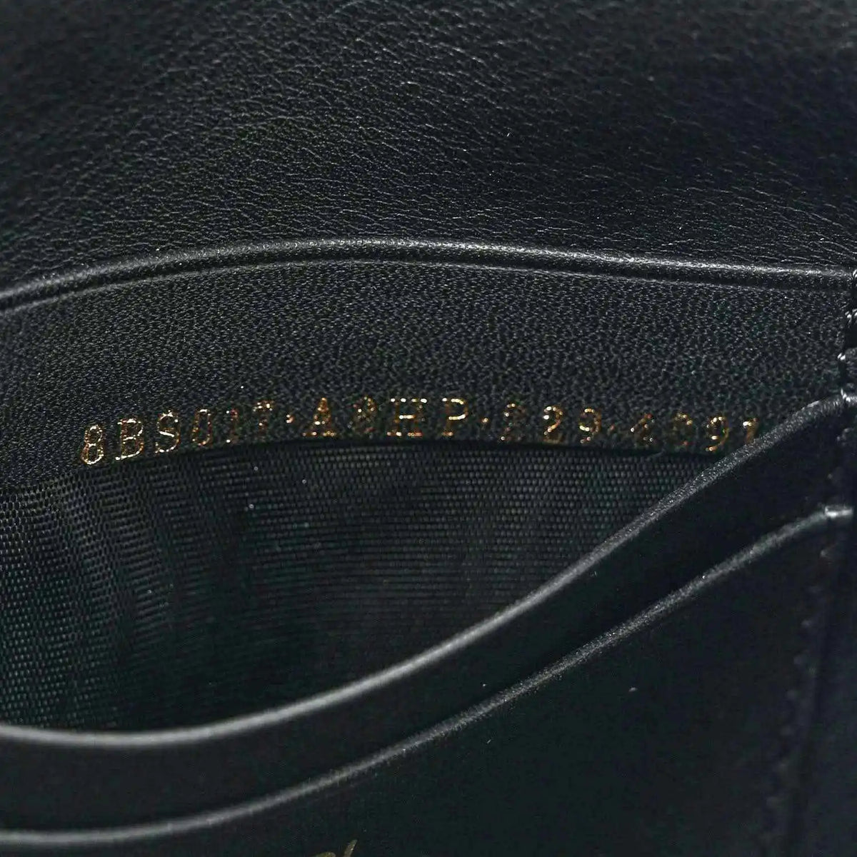 Black leather lining with embossed text, close-up on mini baguette bag.