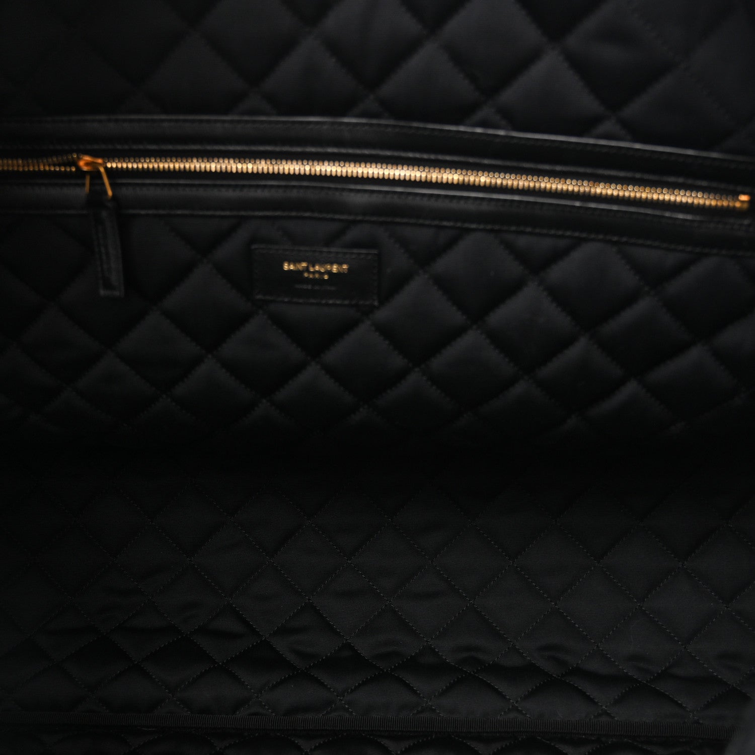 Saint Laurent ES quilted travel bag interior, gold zipper track and black quilted lining.