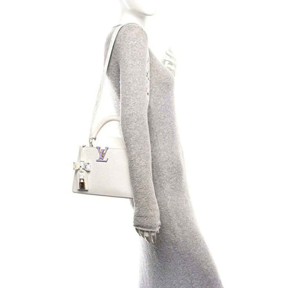 White leather handbag with long gray shoulder strap and gold-tone hardware