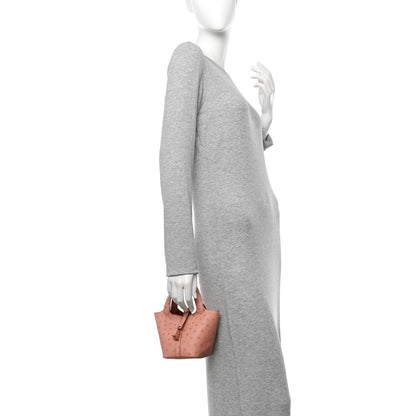 Mini bucket bag in light pink ostrich leather, shown on a person at the side