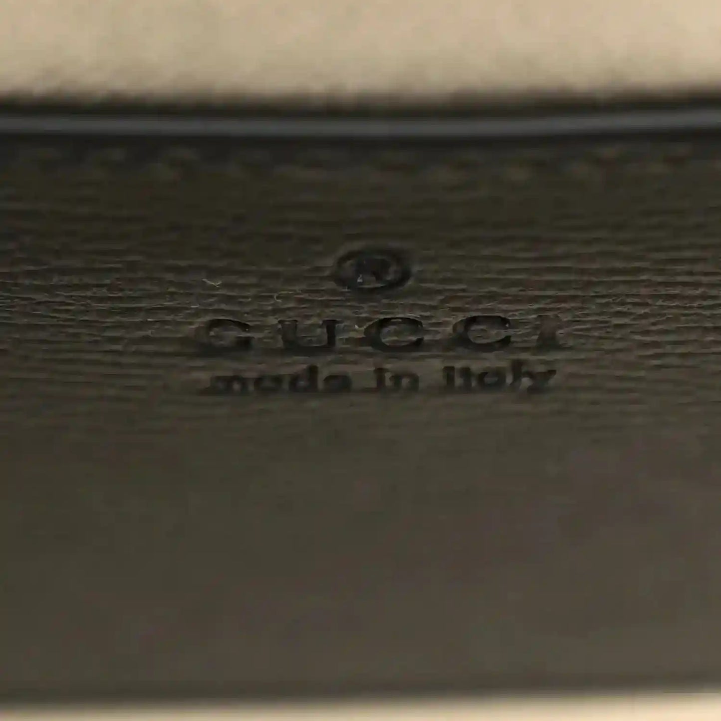 GUCCI embossed logo on dark leather mini bag panel with small icon