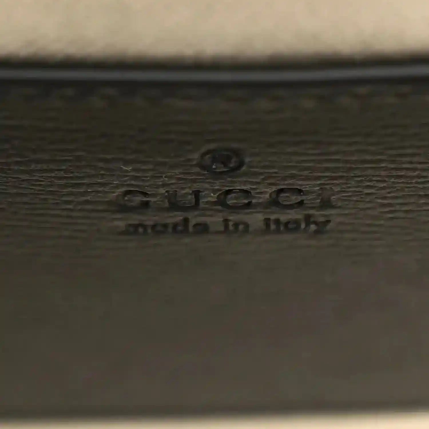 GUCCI embossed logo on dark leather mini bag panel with small icon