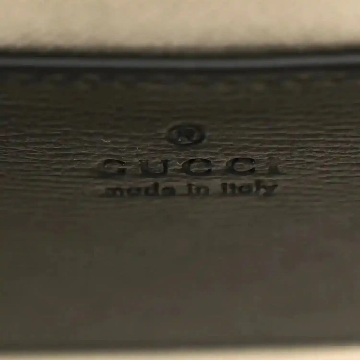 GUCCI embossed logo on dark leather mini bag panel with small icon