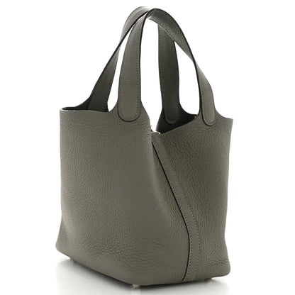 Leather bucket bag side view with curved handles and center zip, dark green