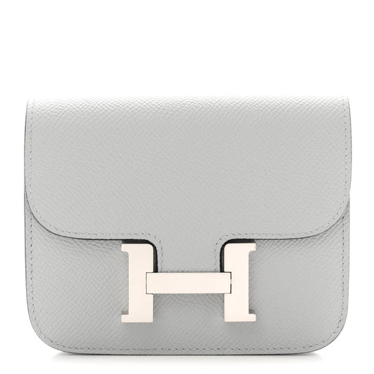 Hermes Constance slim wallet in light blue textured leather with front H clasp.
