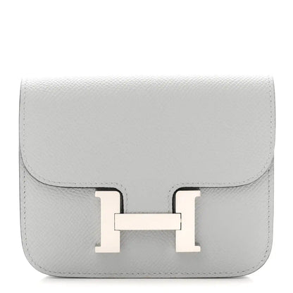 Hermes Constance slim wallet in light blue textured leather with front H clasp.