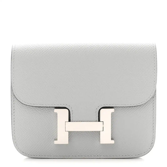 Hermes Constance slim wallet in light blue textured leather with front H clasp.