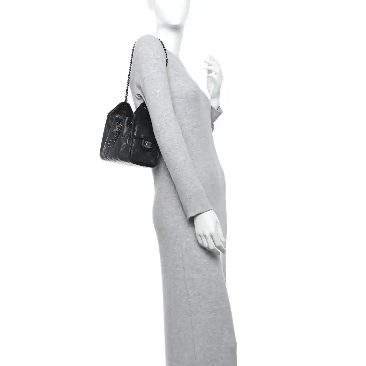 Black quilted mini shoulder bag with chain strap, worn crossbody on model.