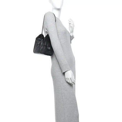 Black quilted mini shoulder bag with chain strap, worn crossbody on model.