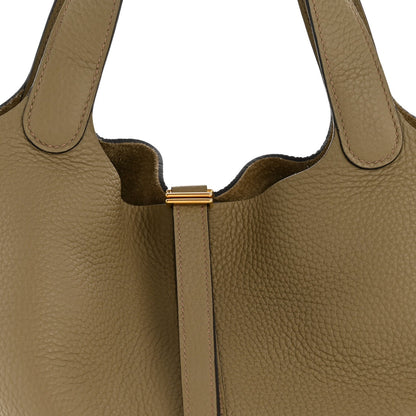 Beige leather tote with gold-tone strap lock and textured panel close-up