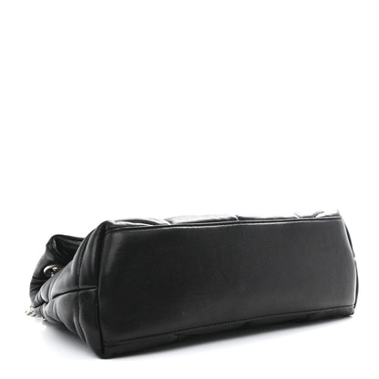 Black quilted lambskin puffer small satchel side view with smooth flap and rounded base.