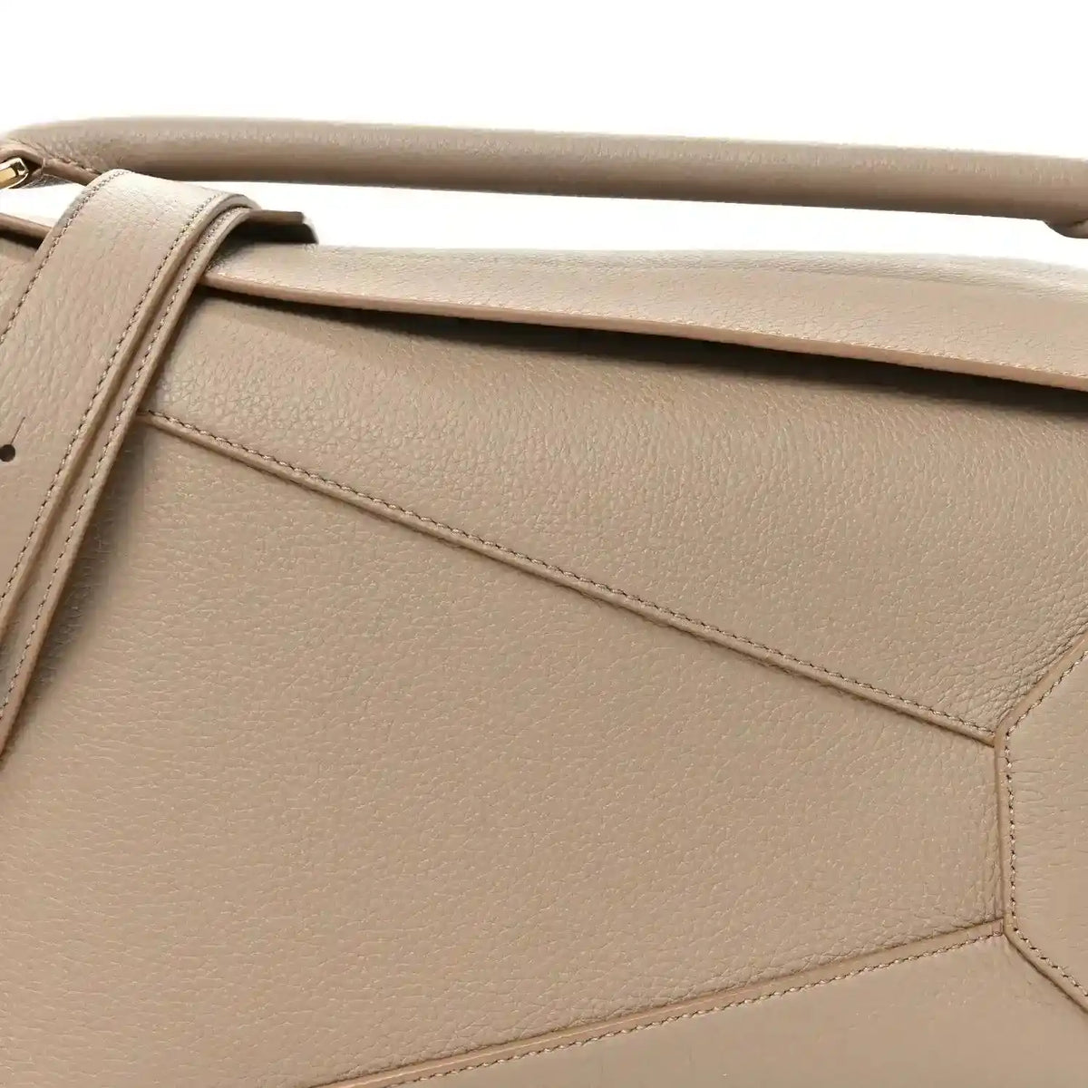 Sand leather bag front panel with diagonal seam detailing and gold-tone edge hardware.