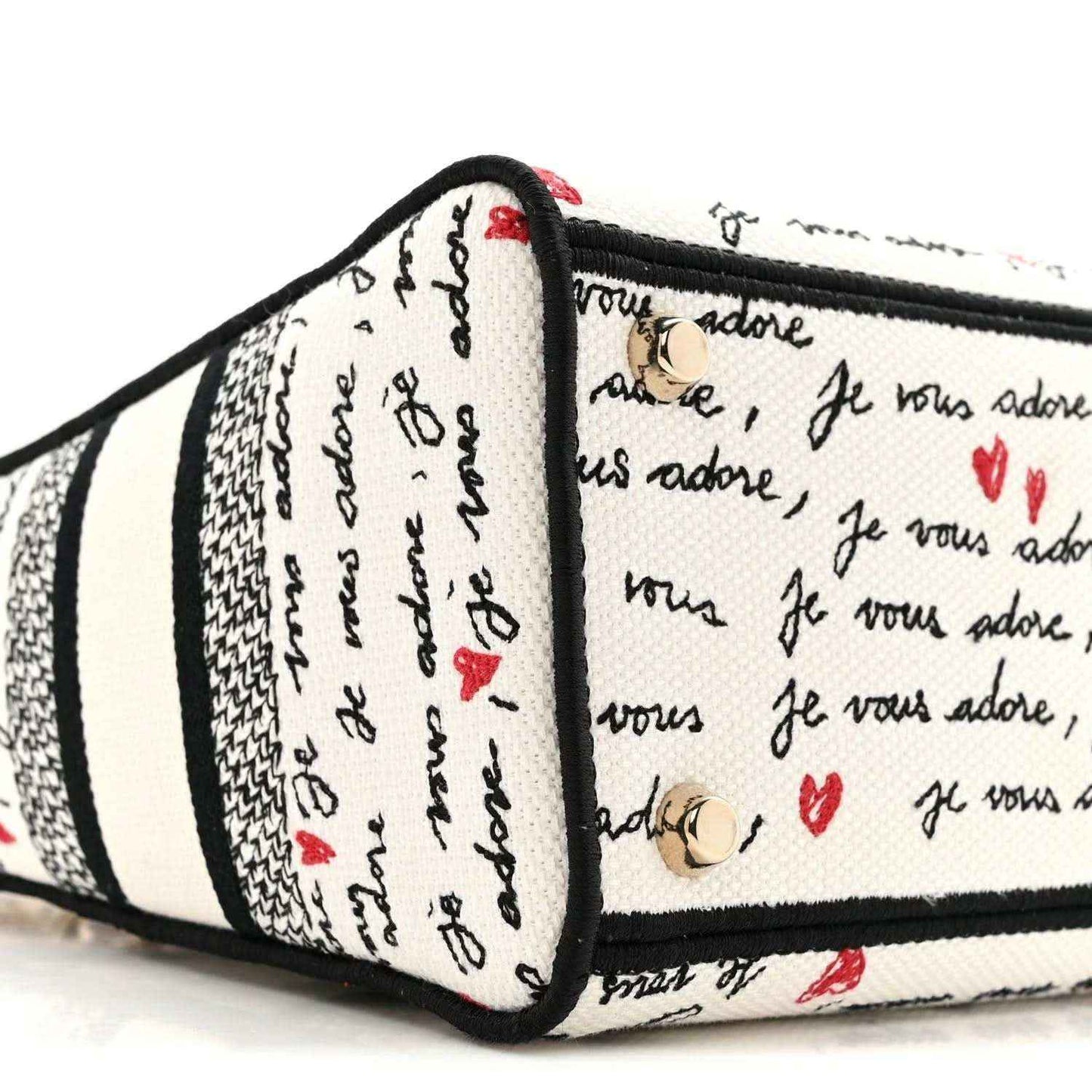Christian Dior canvas handbag side view, black-trimmed edges, “Je vous adore” print