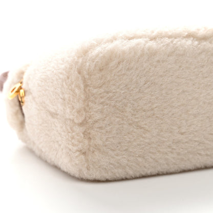 Side view of cream faux-fur pouch with small gold zipper hardware