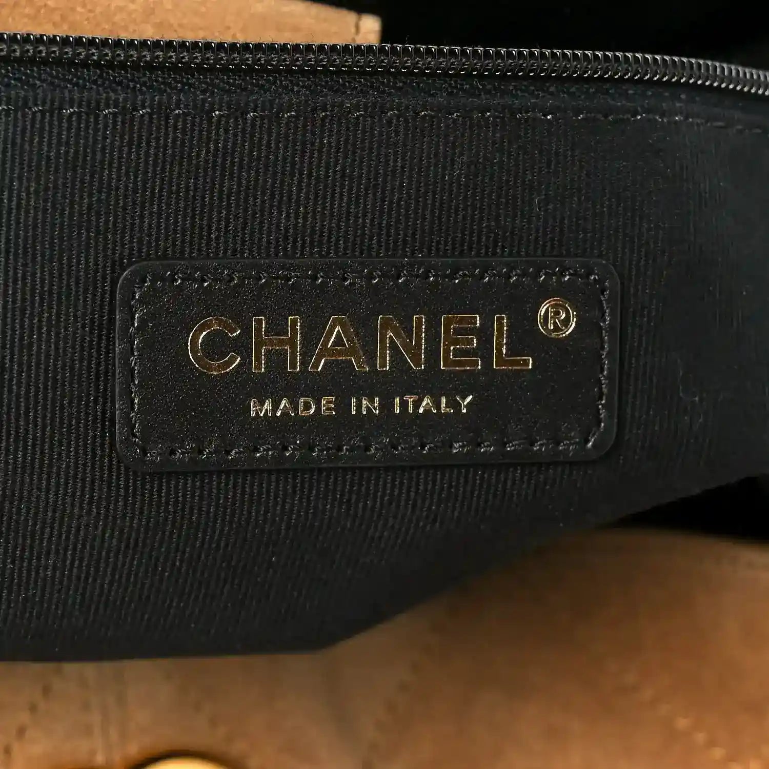 CHANEL logo patch on black fabric lining with gold text and zipper edge
