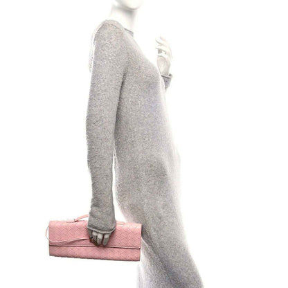 Rose pink woven nappa leather clutch with top handle, worn at side