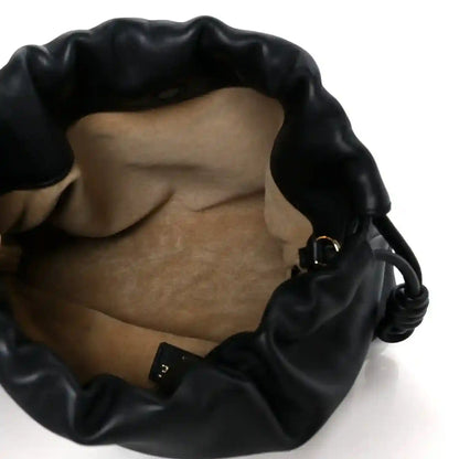 Black leather clutch interior showing soft lining and small metal detail at base.