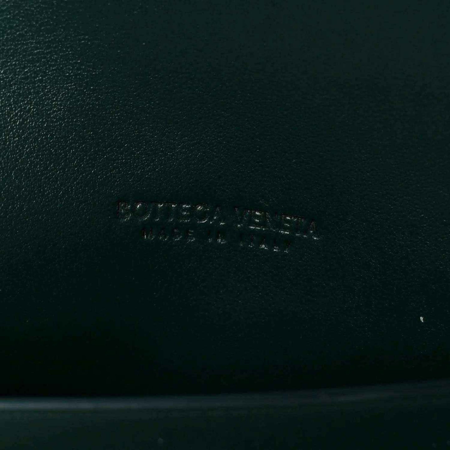Emerald green nappa clutch bag with embossed brand mark on leather