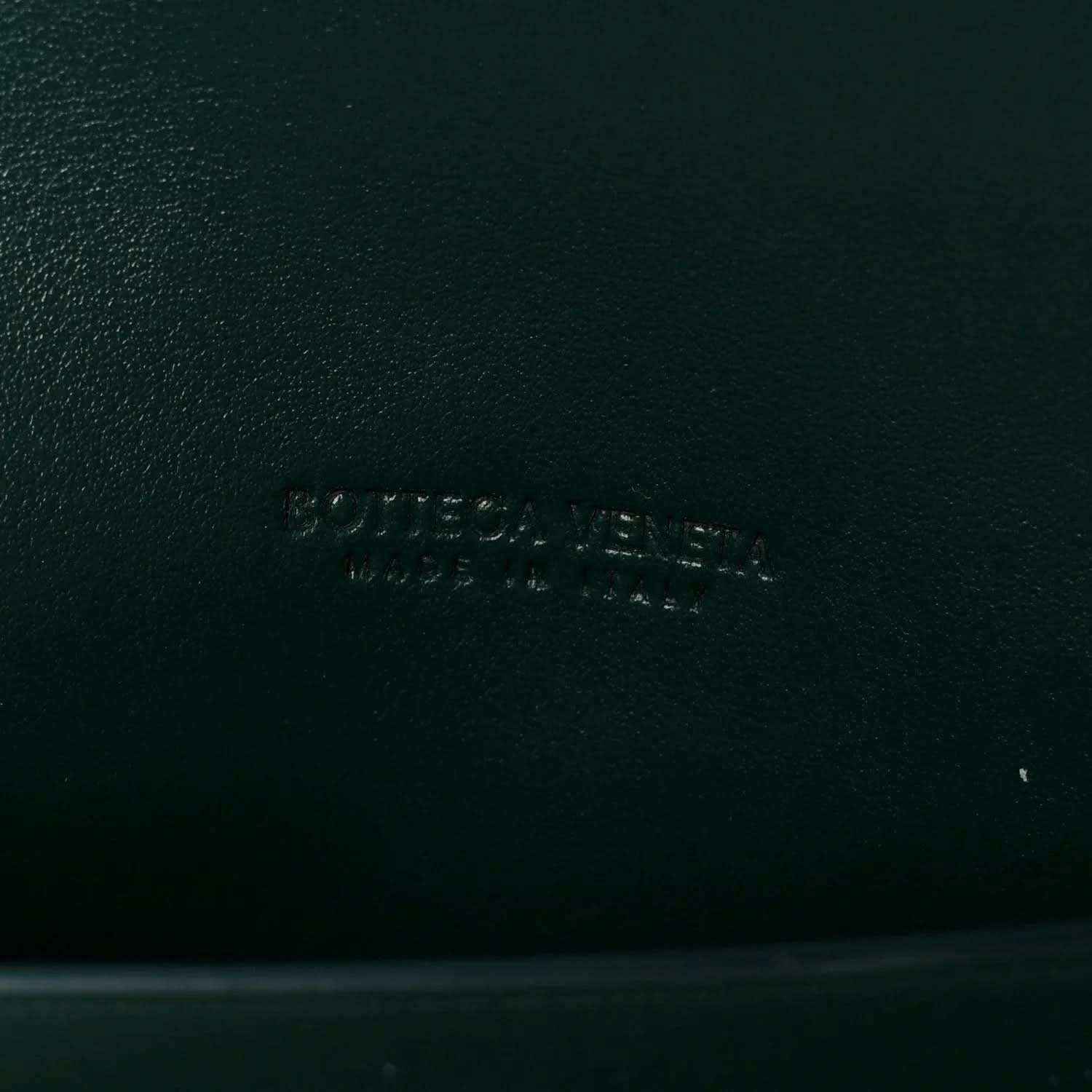 Emerald green nappa clutch bag with embossed brand mark on leather