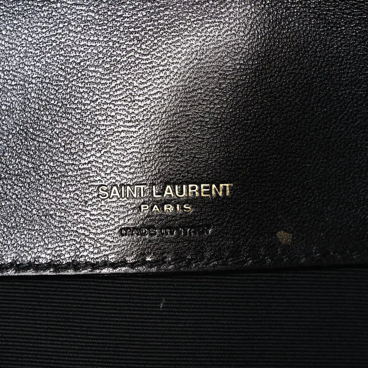 Black leather bag with SAINT LAURENT PARIS logo stamp on textured finish