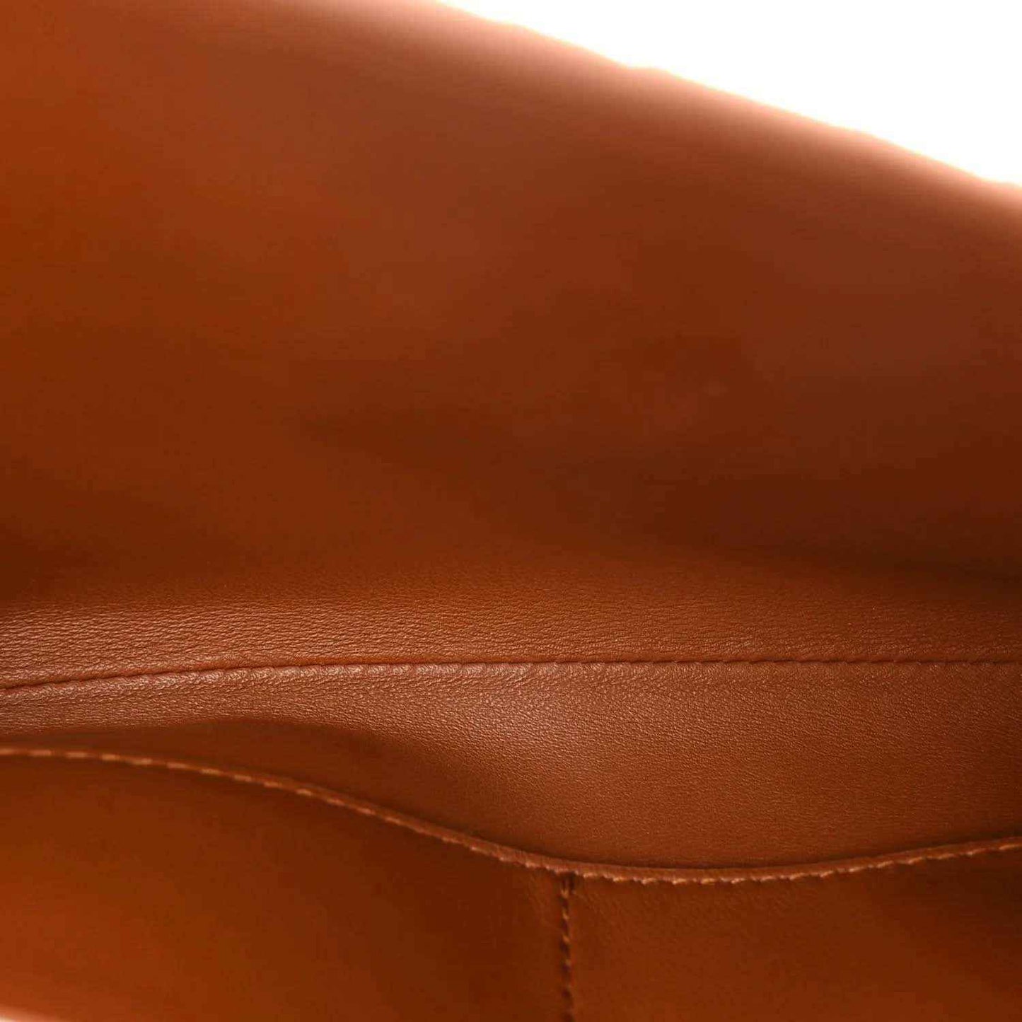 Amber-brown leather trim seam on suede clutch flap