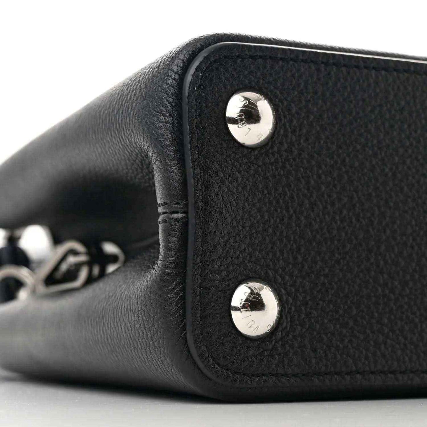 Black leather handbag side panel with two silver snap buttons and short handle
