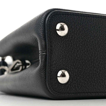 Black leather handbag side panel with two silver snap buttons and short handle