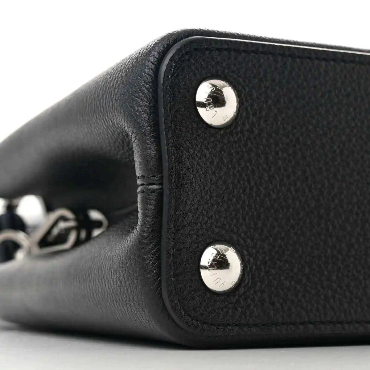 Black leather handbag side panel with two silver snap buttons and short handle