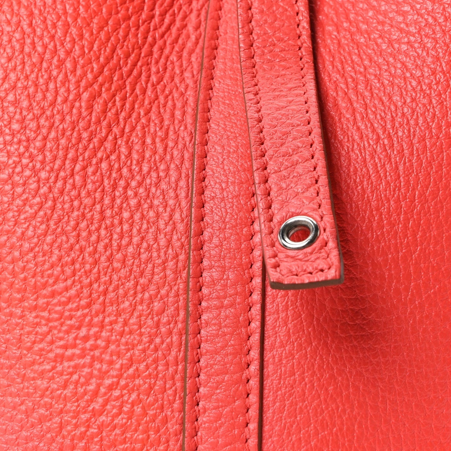 Red leather tote side seam with braided trim and metal grommet ring