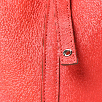 Red leather tote side seam with braided trim and metal grommet ring