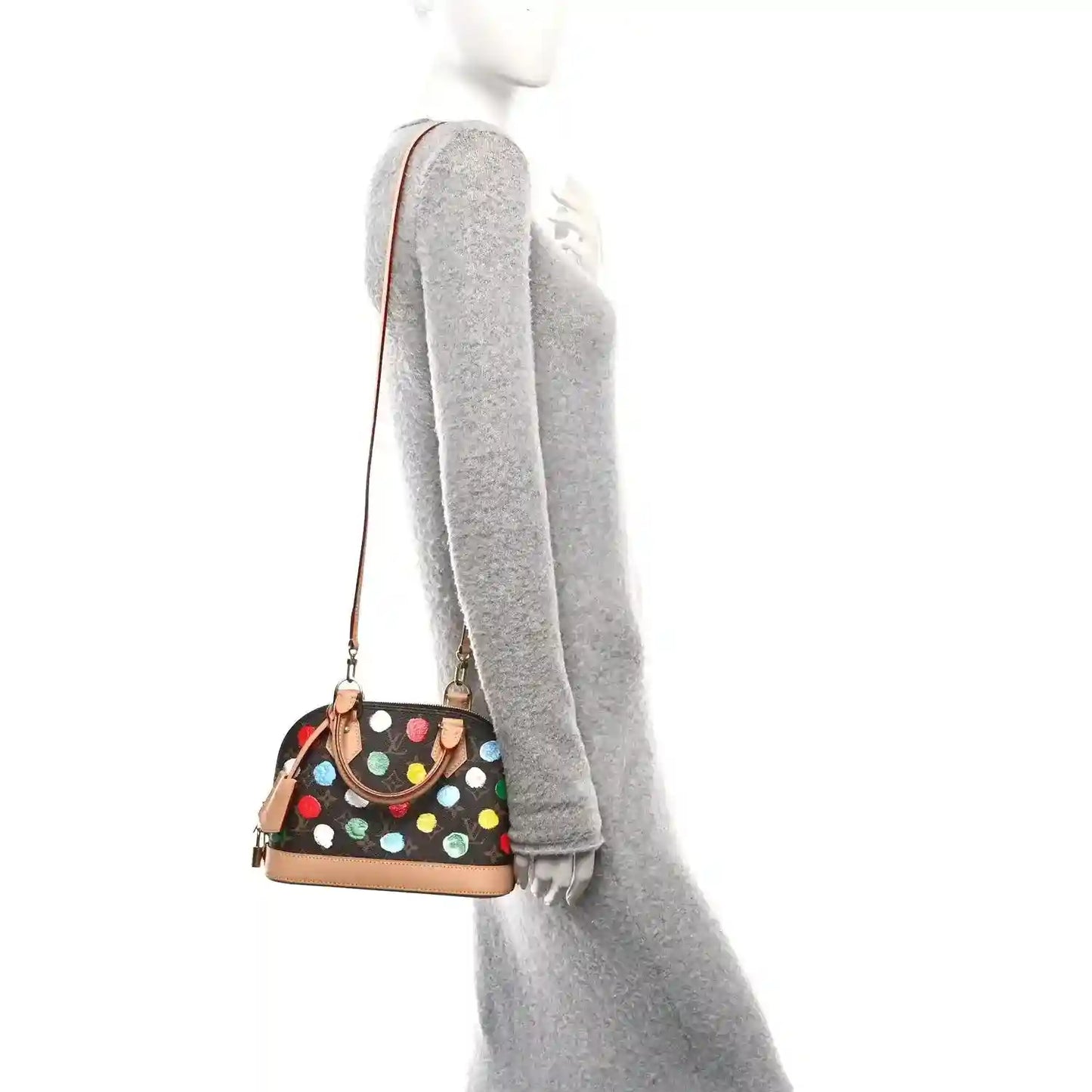 Small dot-print handbag worn at side with tan strap and top zip closure.