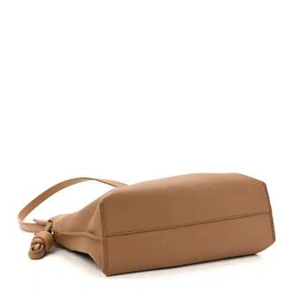 Tan mini clutch bag with single strap and looped knotted detail at the side.